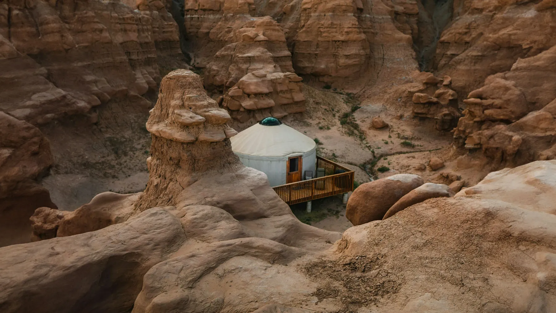 A yurt with a wooden deck among sandstone rocks